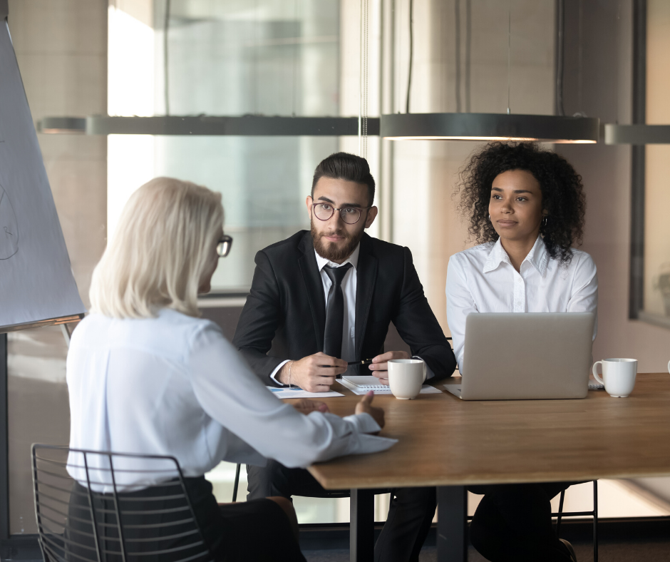 three professionals at table discussing Layoffs vs. Furloughs