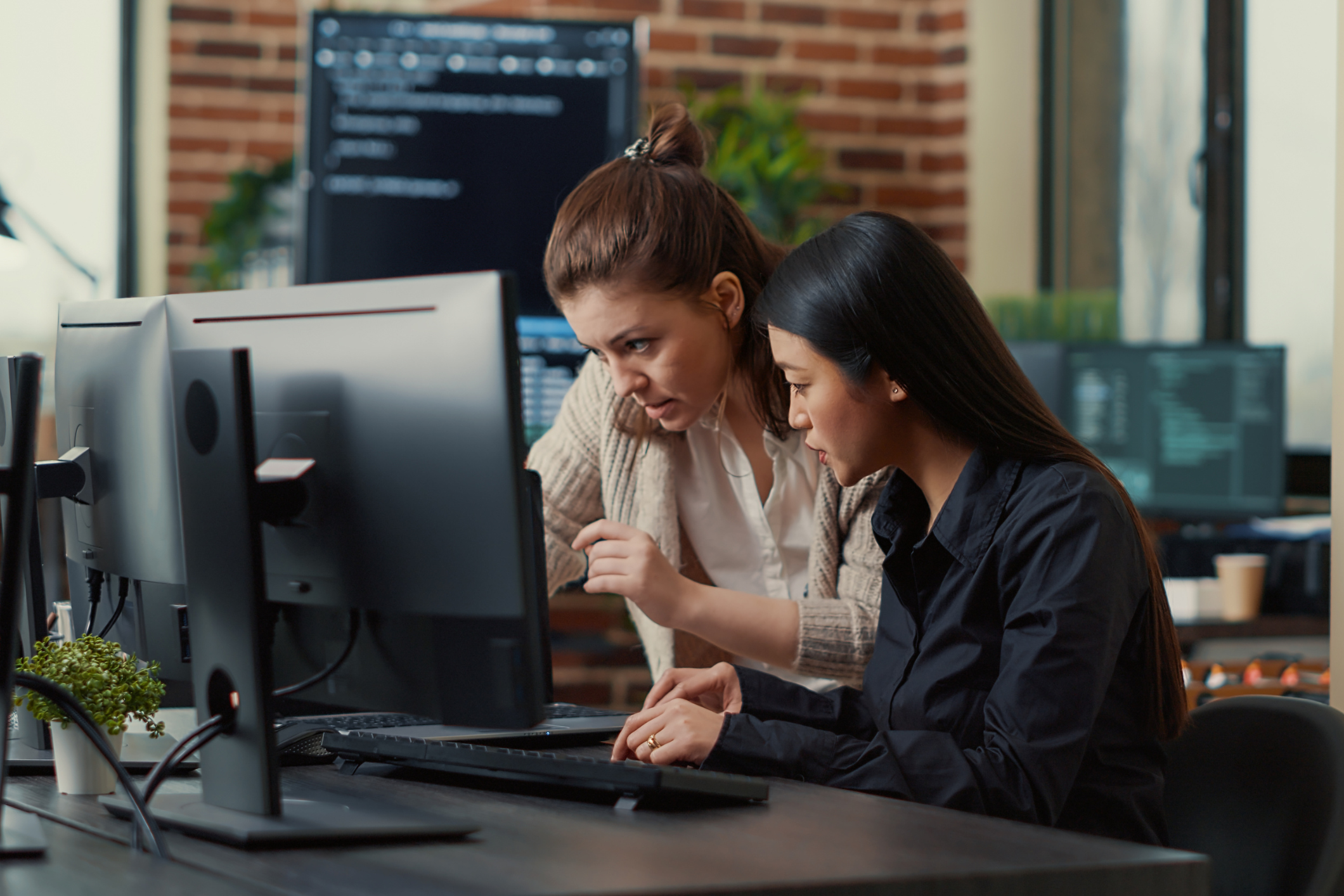 Photo of two female employees working at a computer together