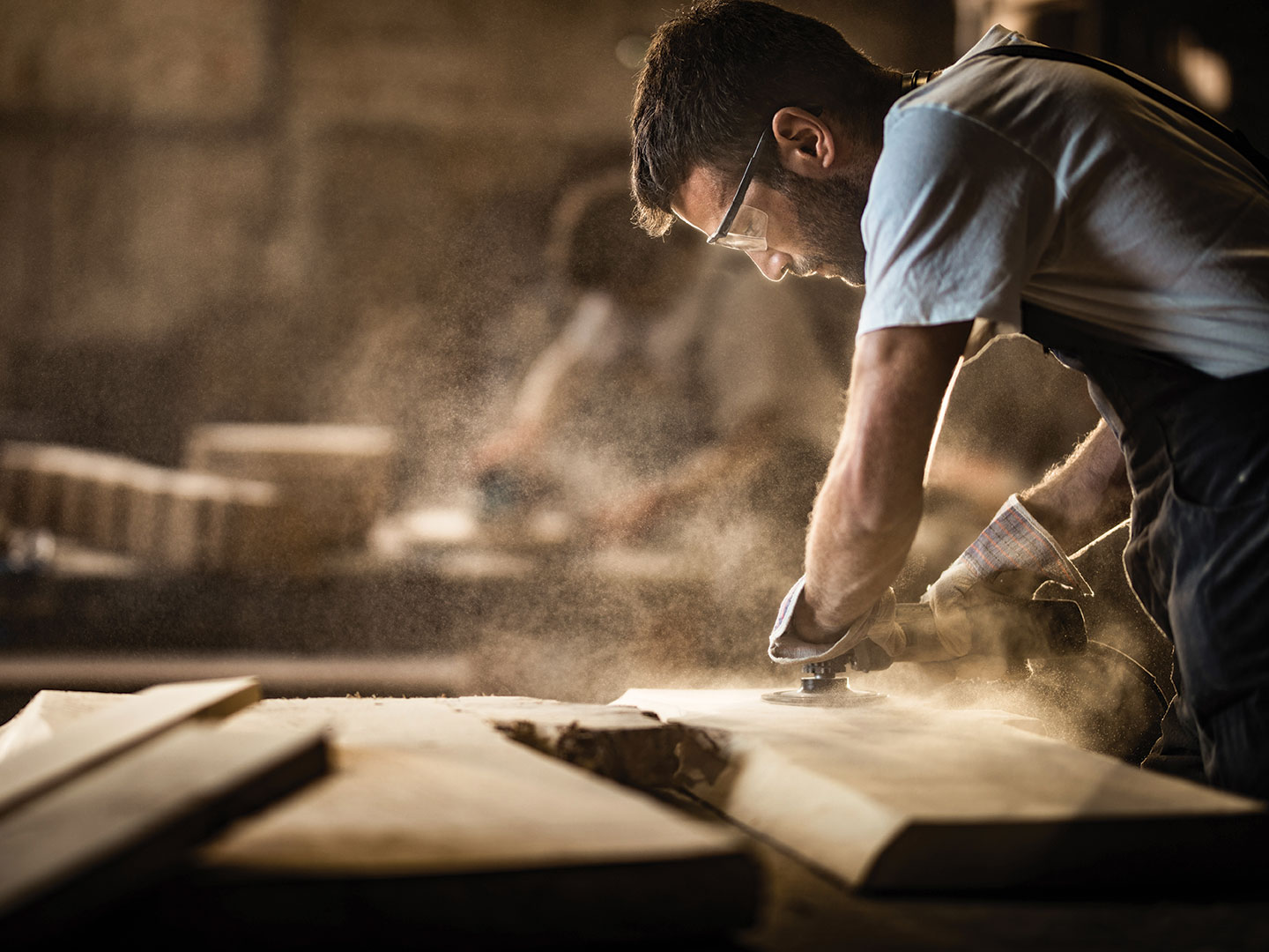 A carpenter using equipment to sand wood