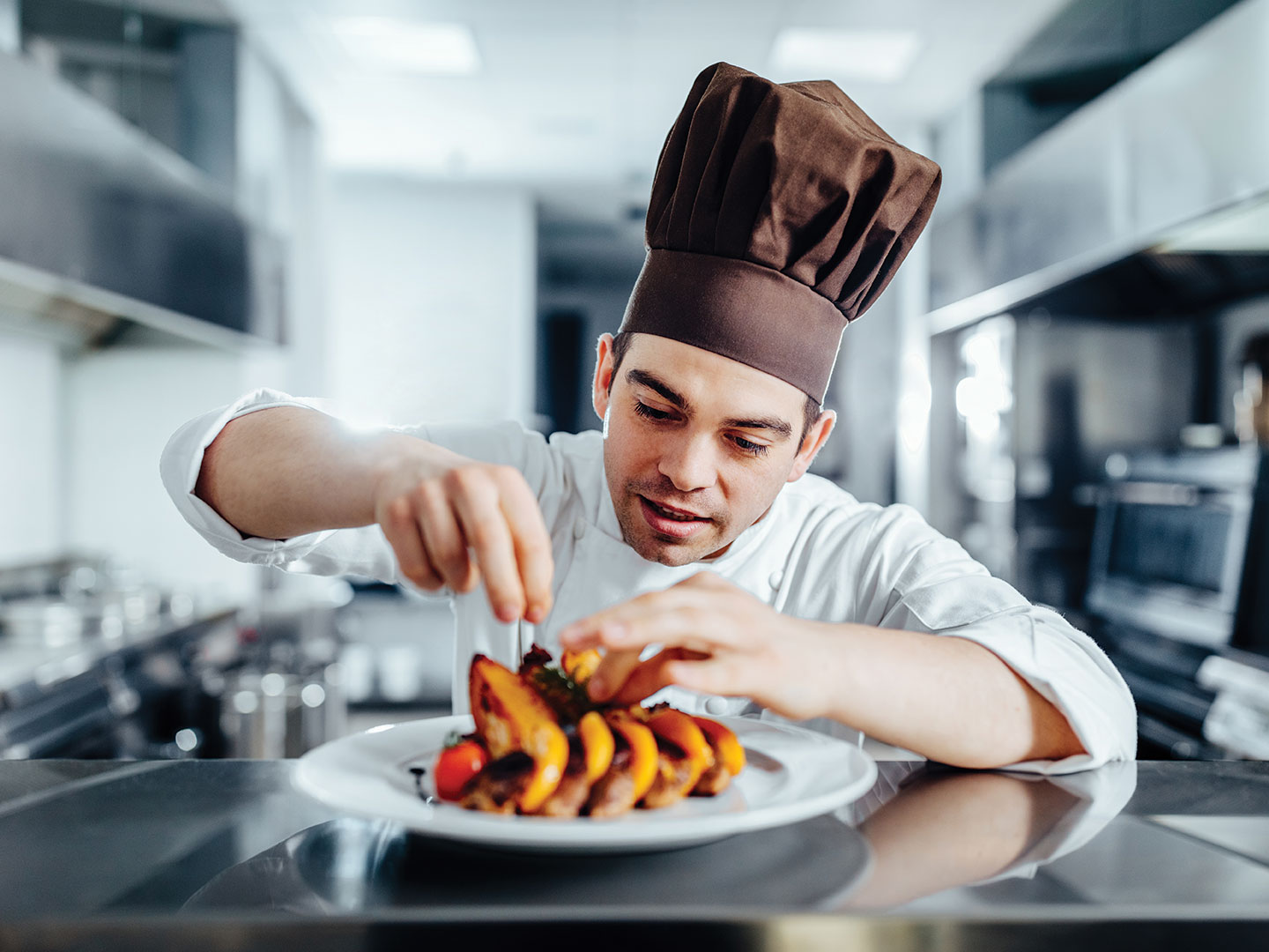 A chef finishes preparing a plate of food for a customer