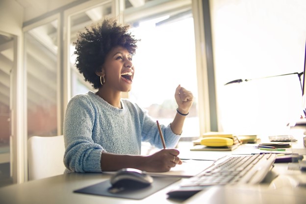 Help is Here: Hospitality Industry hero shot; woman happy at desktop computer