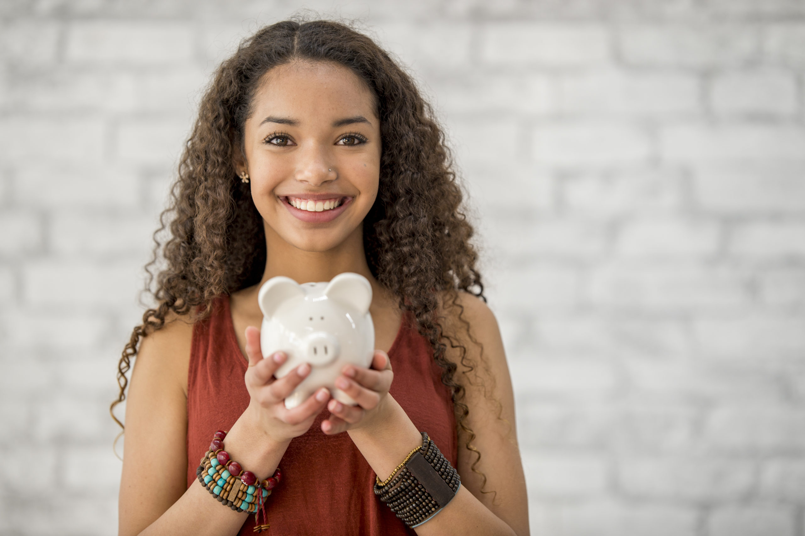 girl holding piggy bank improving her financial well-being